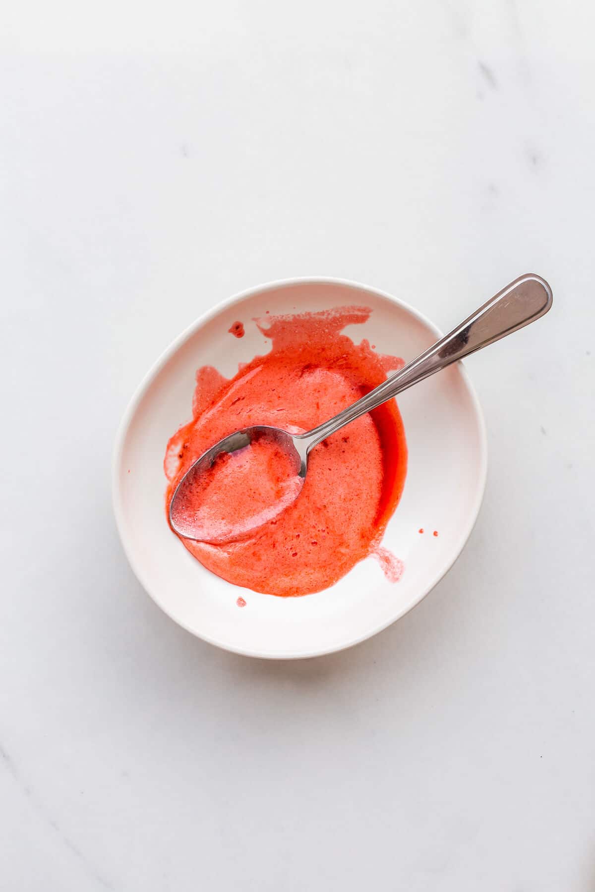 A bowl with the foam skimmed off a pot of strawberry rhubarb jam.