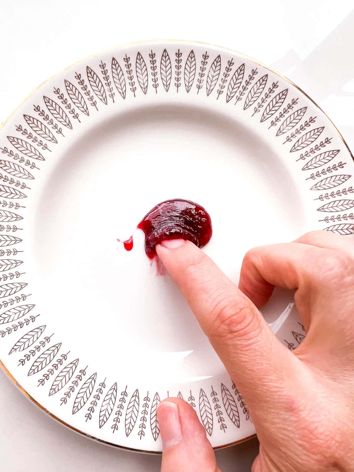 Performing the freezer plate test on a dollop of jam. The jam wrinkles when pushed with a fingertip, showing that it has boiled enough to hit the jam setting point.