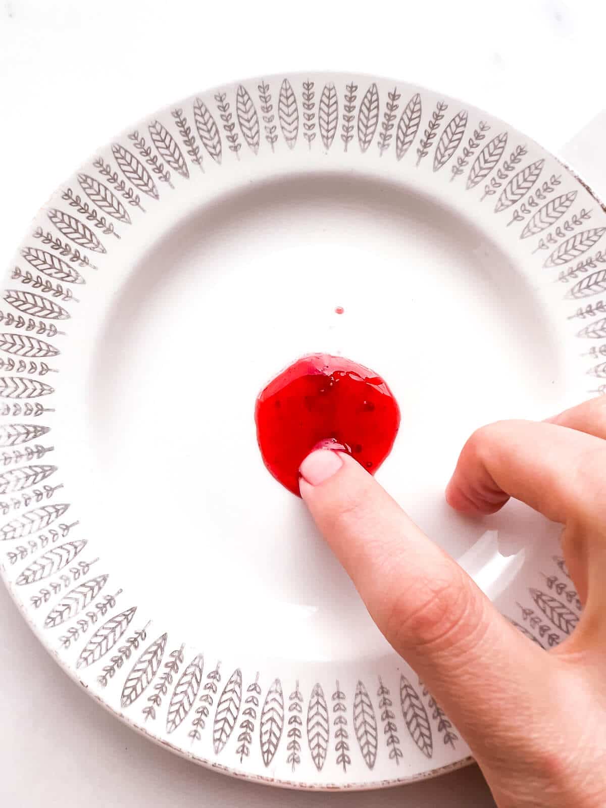 Testing the set of a dollop of jam on a frozen plate. The dollop of jam is too soft and fluid and will have to be boiled more to hit the jam setting point.