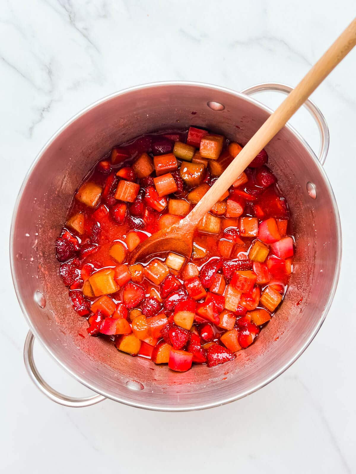 Macerated strawberries and rhubarb with sugar in a pot, ready to make jam.