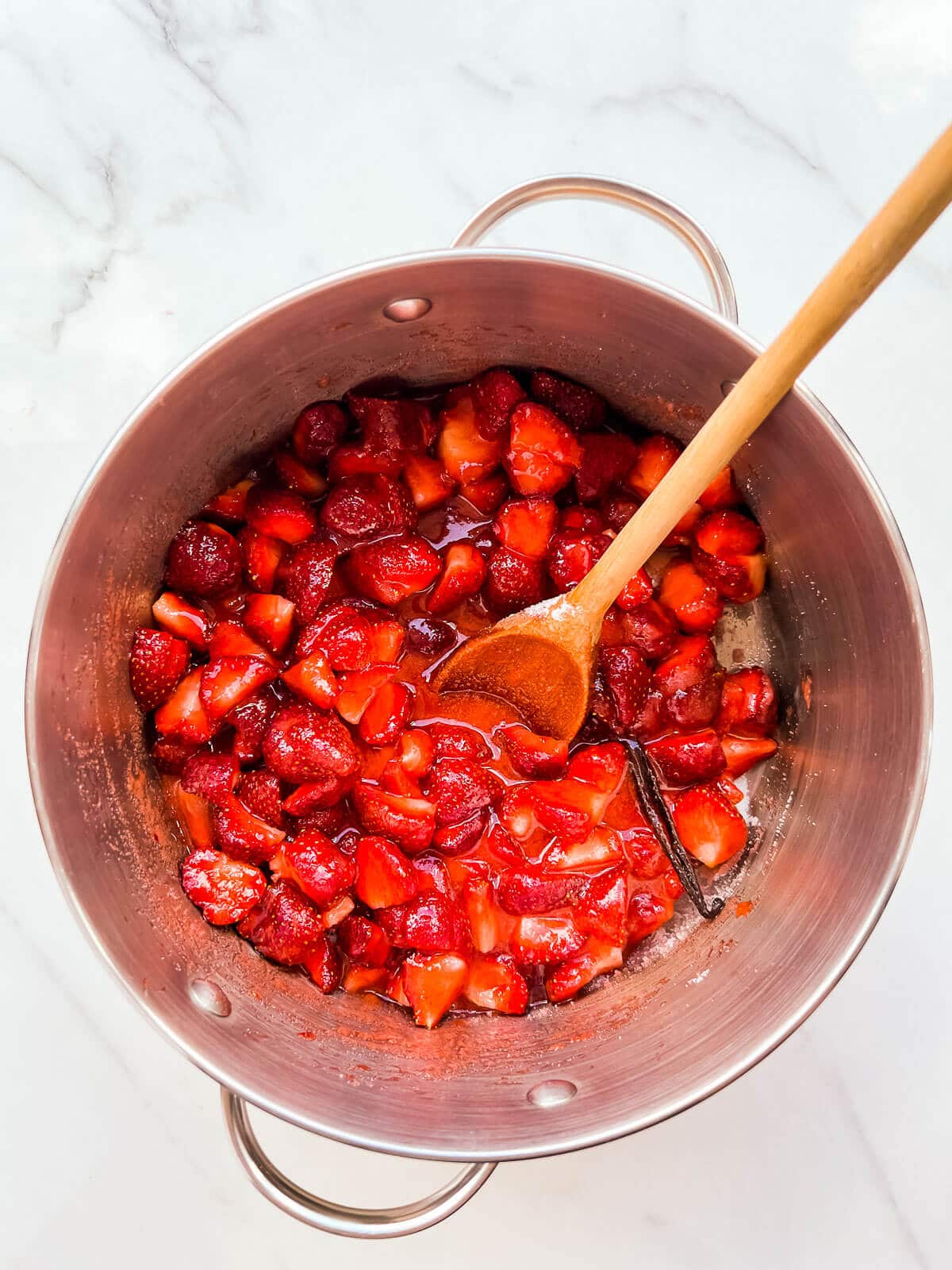 Strawberries macerated in sugar with lemon juice and a vanilla bean to make homemade jam.