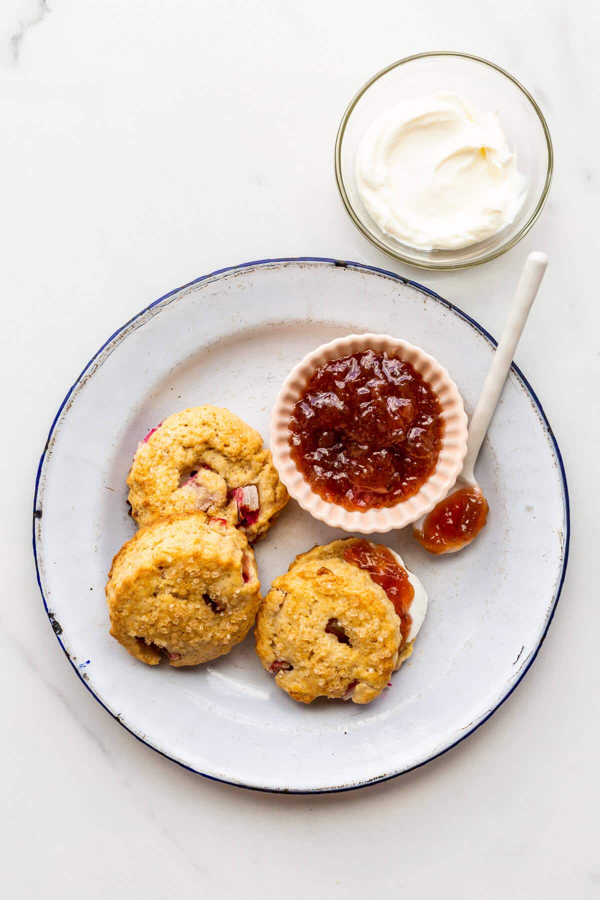 A plate of rhubarb scones served with jam and cream.