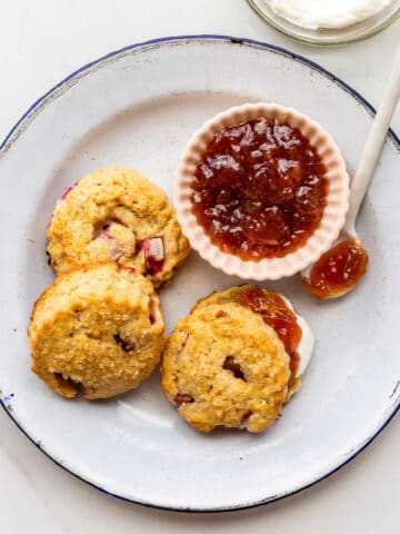 A plate of scones with rhubarb served with jam.