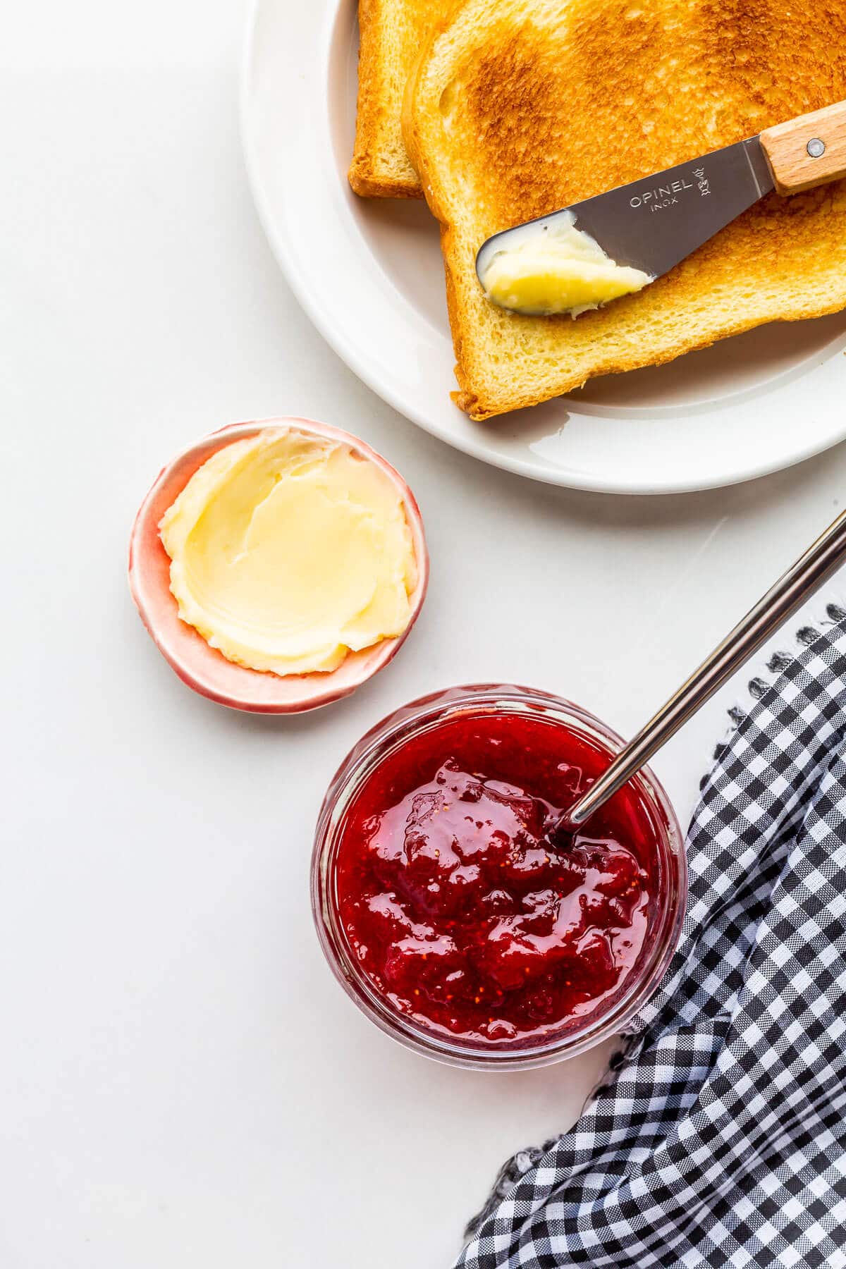 A jar of strawberry jam with rhubarb to be served with toast.