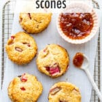 Rhubarb scones on a cooling rack with a bowl of jam.