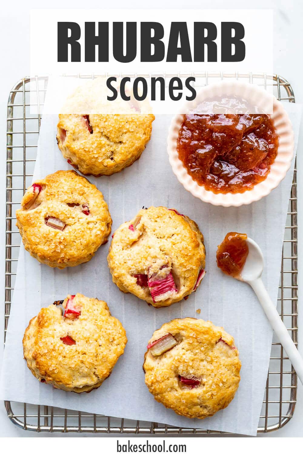 Rhubarb scones on a cooling rack with a bowl of jam.