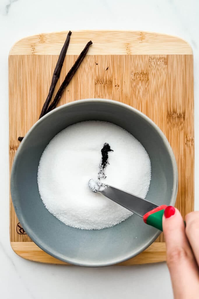 Adding vanilla bean seeds to a bowl of sugar to flavour it.