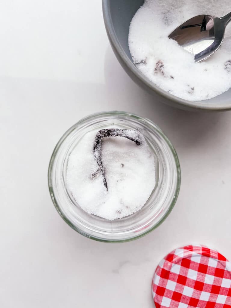 Transferring homemade vanilla sugar made with a vanilla bean to a jar to store it.