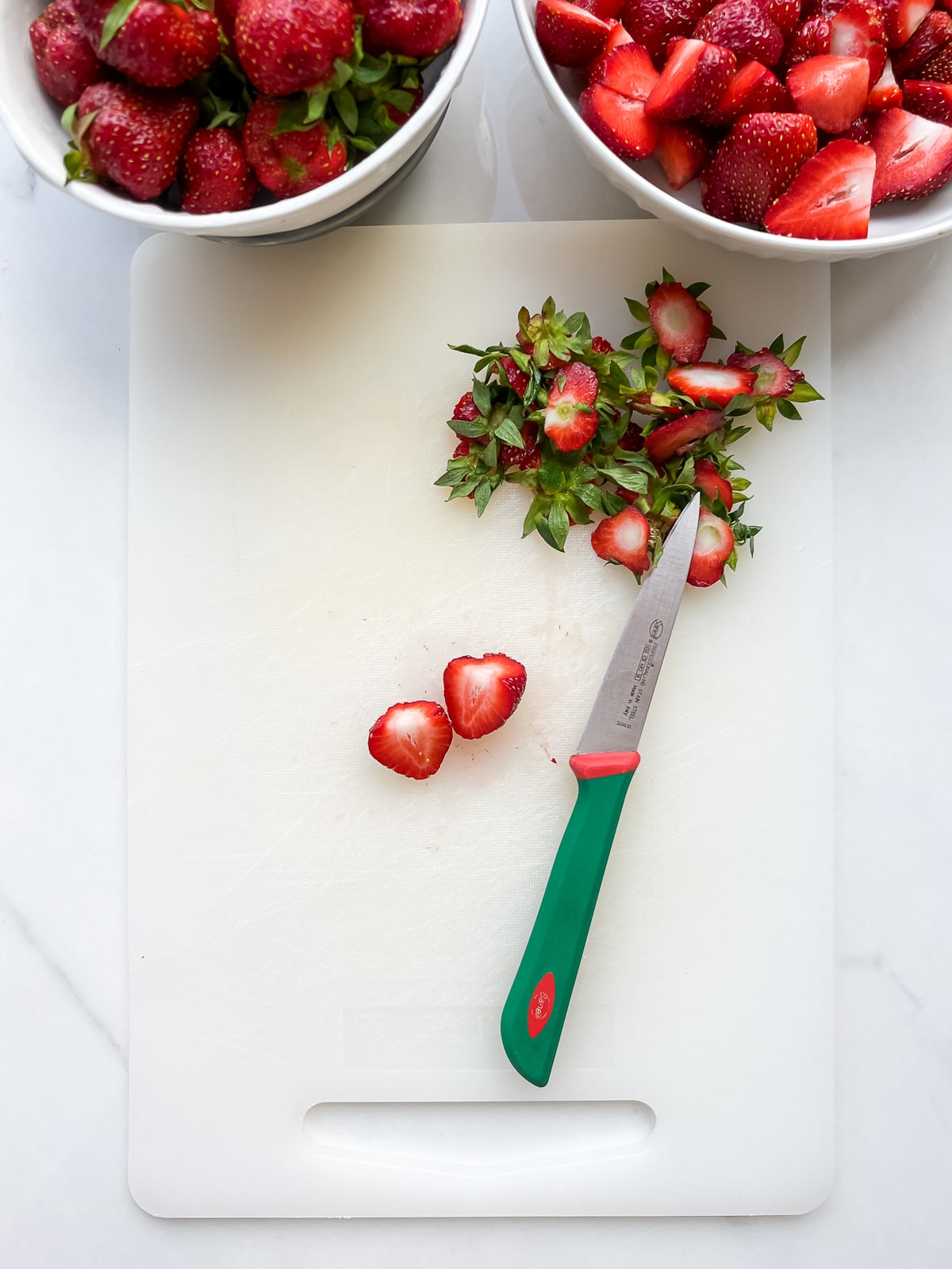 Hulling washed strawberries and chopping to make homemade jam.