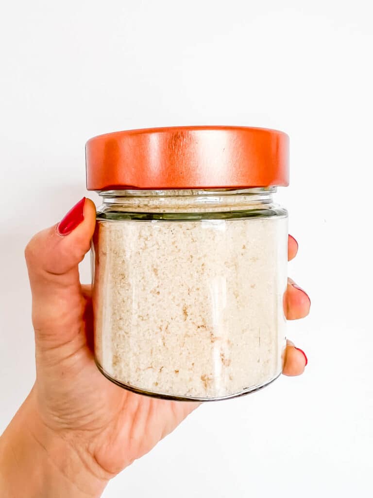 A jar of vanilla sugar made from vanilla extract so it has a slightly golden colour.