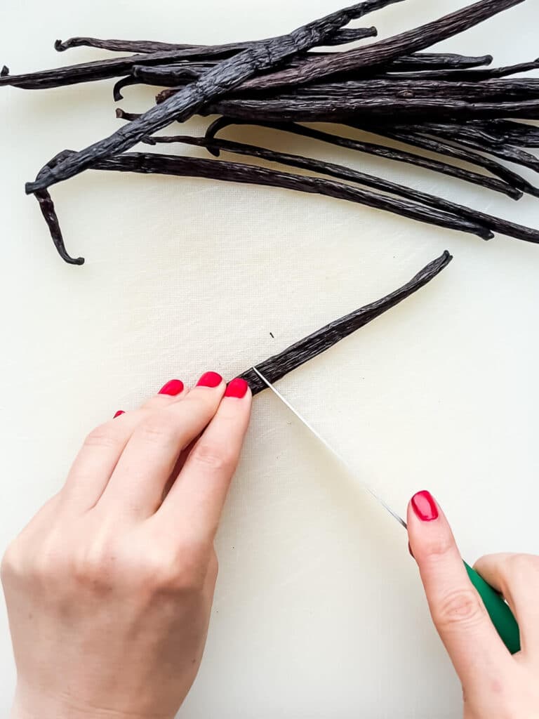 Cutting vanilla beans in half to fit them in a jar and make pure vanilla extract.