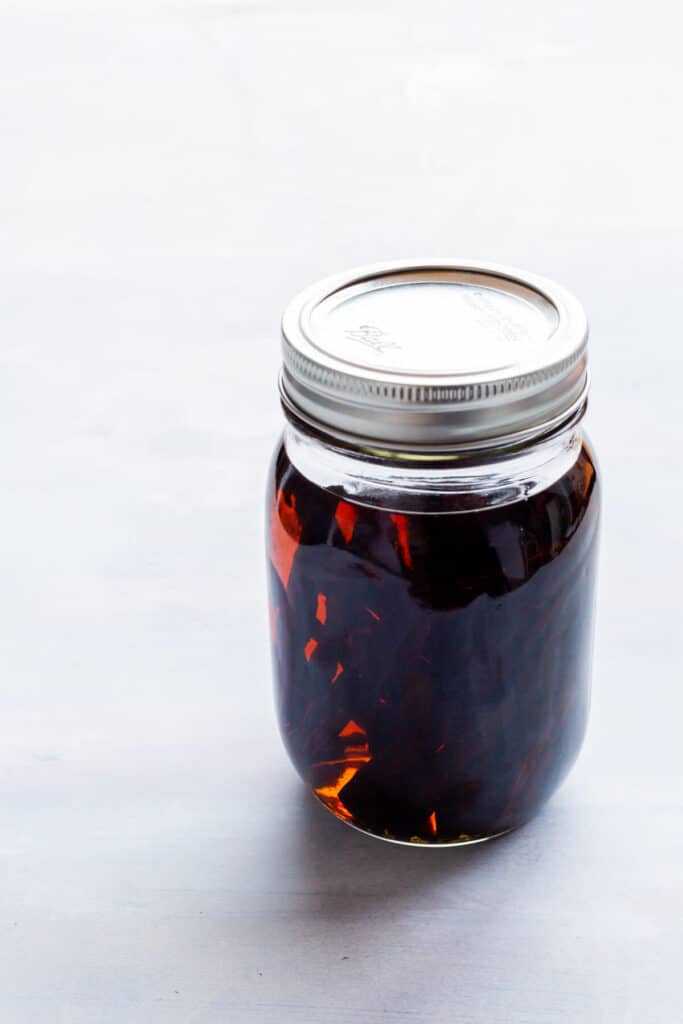 A jar of homemade vanilla extract with whole beans soaking inside.