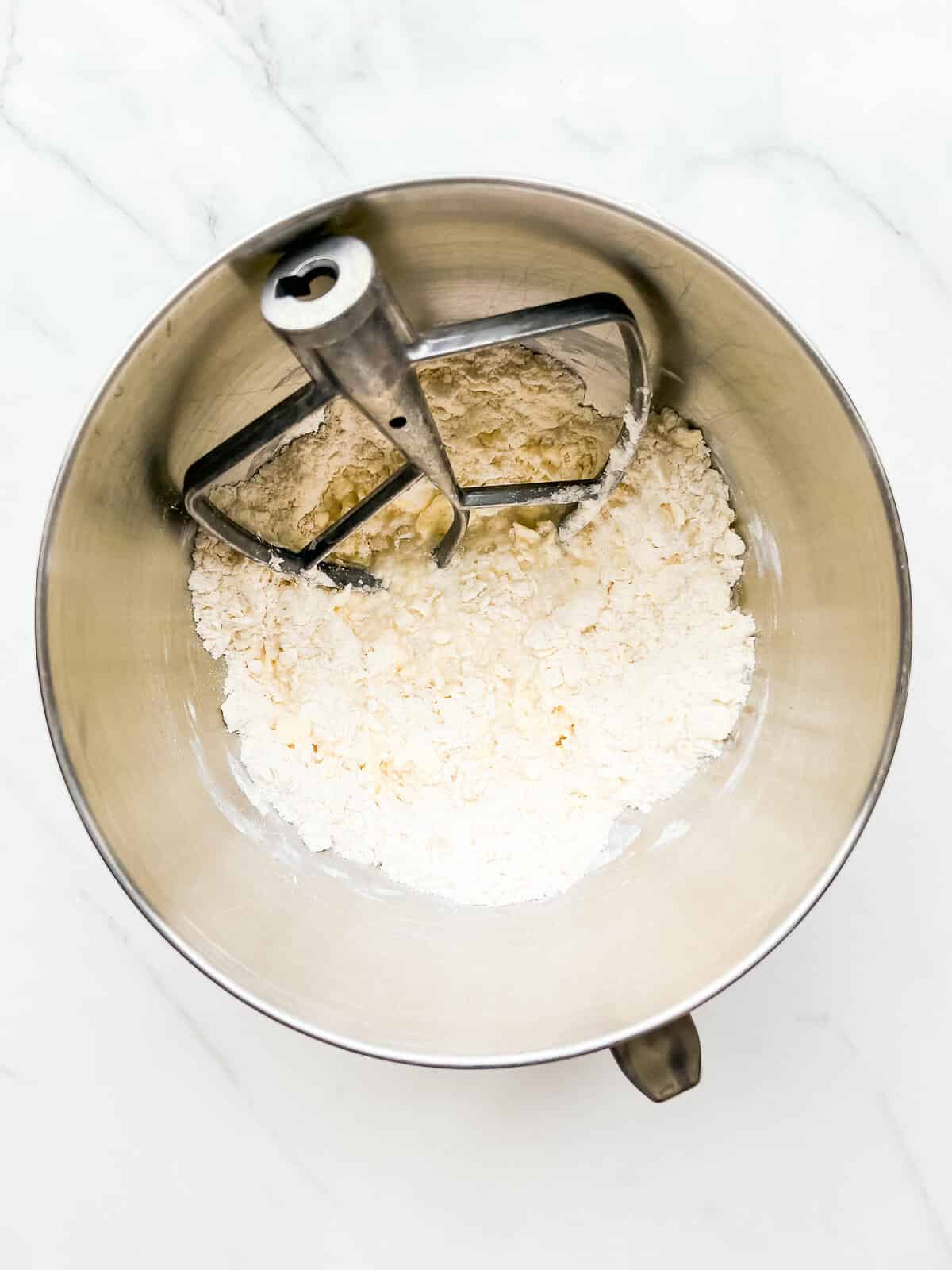 Electric whisk in mixing bowl with butter and flour