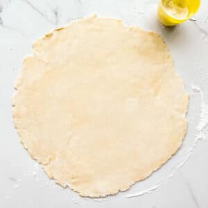 Pie dough rolled out into a round, thin sheet to make a pie crust.