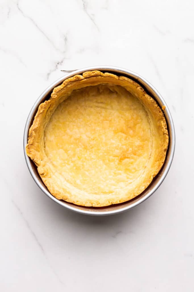 A blind baked pie crust in a 9 inch springform pan ready to be filled for a deep dish quiche.