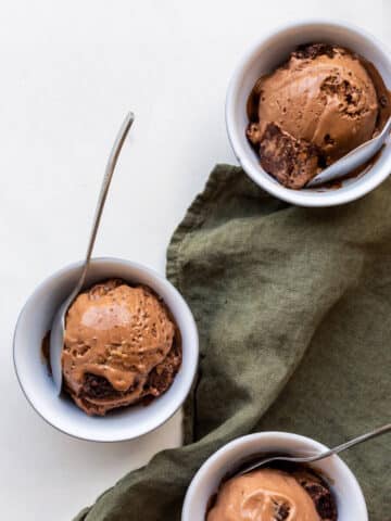 Chocolate brownie ice cream scooped into three small grey bowls with spoons.