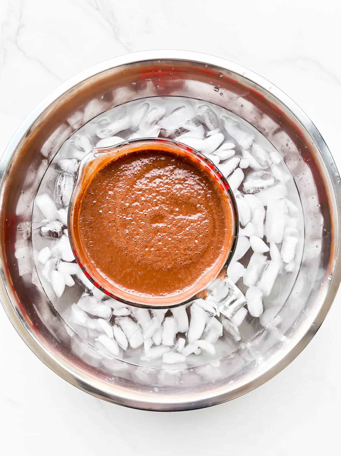 Chilling a chocolate custard ice cream base in an ice bath to cool it down quickly.