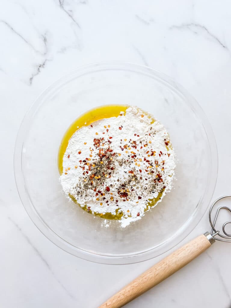 Dry ingredients plus olive oil and spices in a bowl to make dough for crackers.