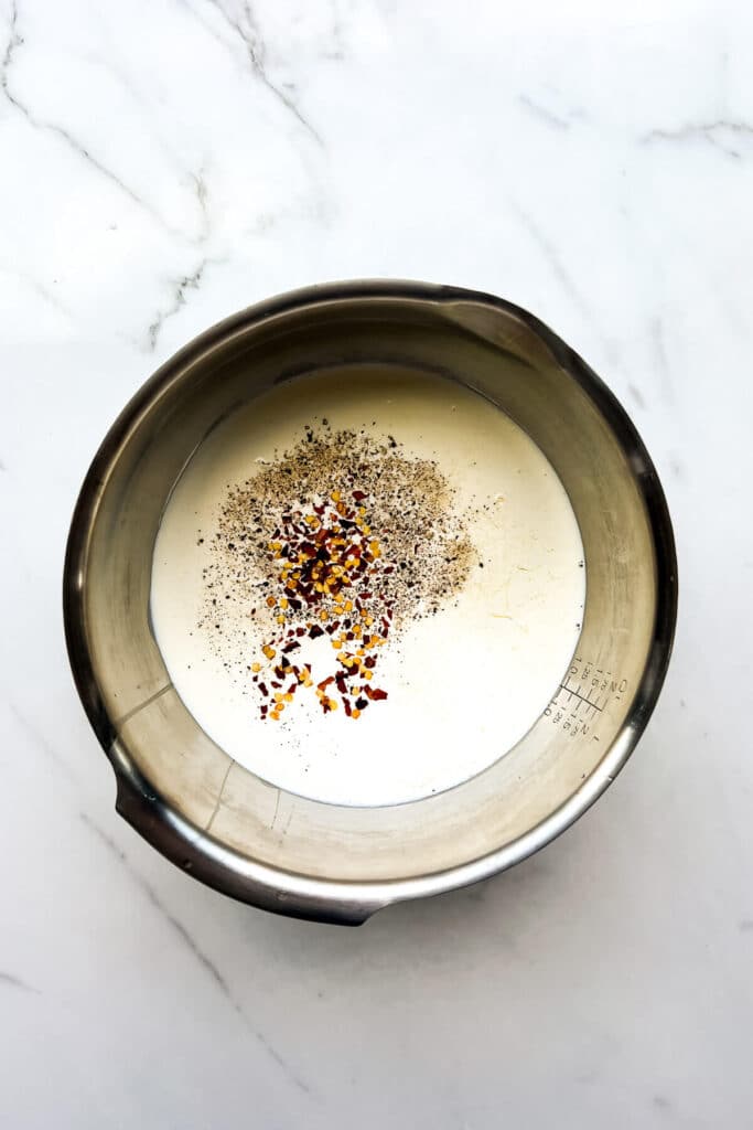 Making the savoury custard filling for a quiche with cream, eggs, milk, and spices.