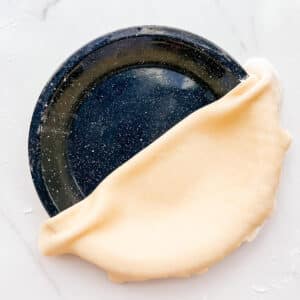 Transferring pie dough to a pie plate to make a pie crust.