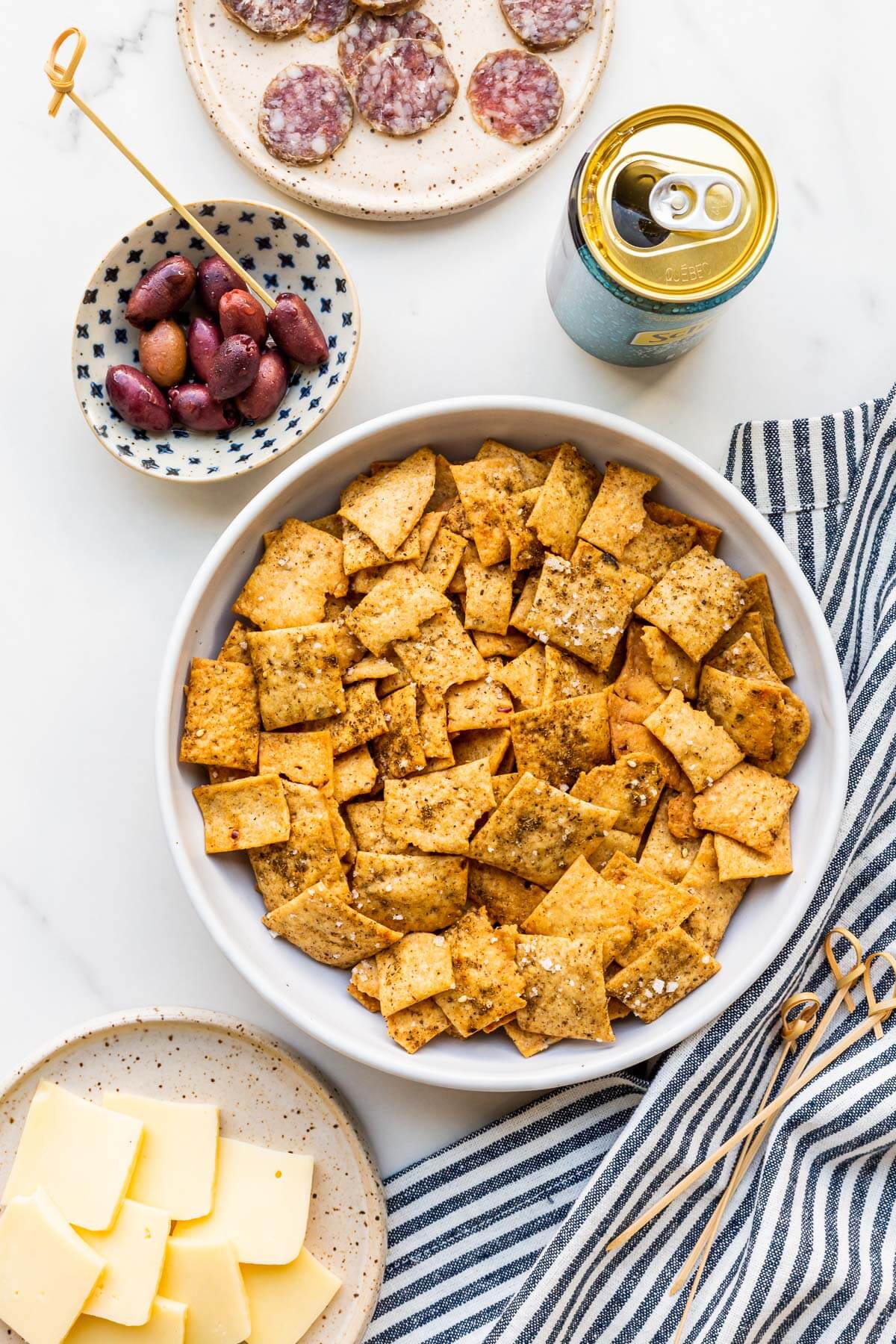 A bowl of homemade crackers served with cheese and charcuterie.