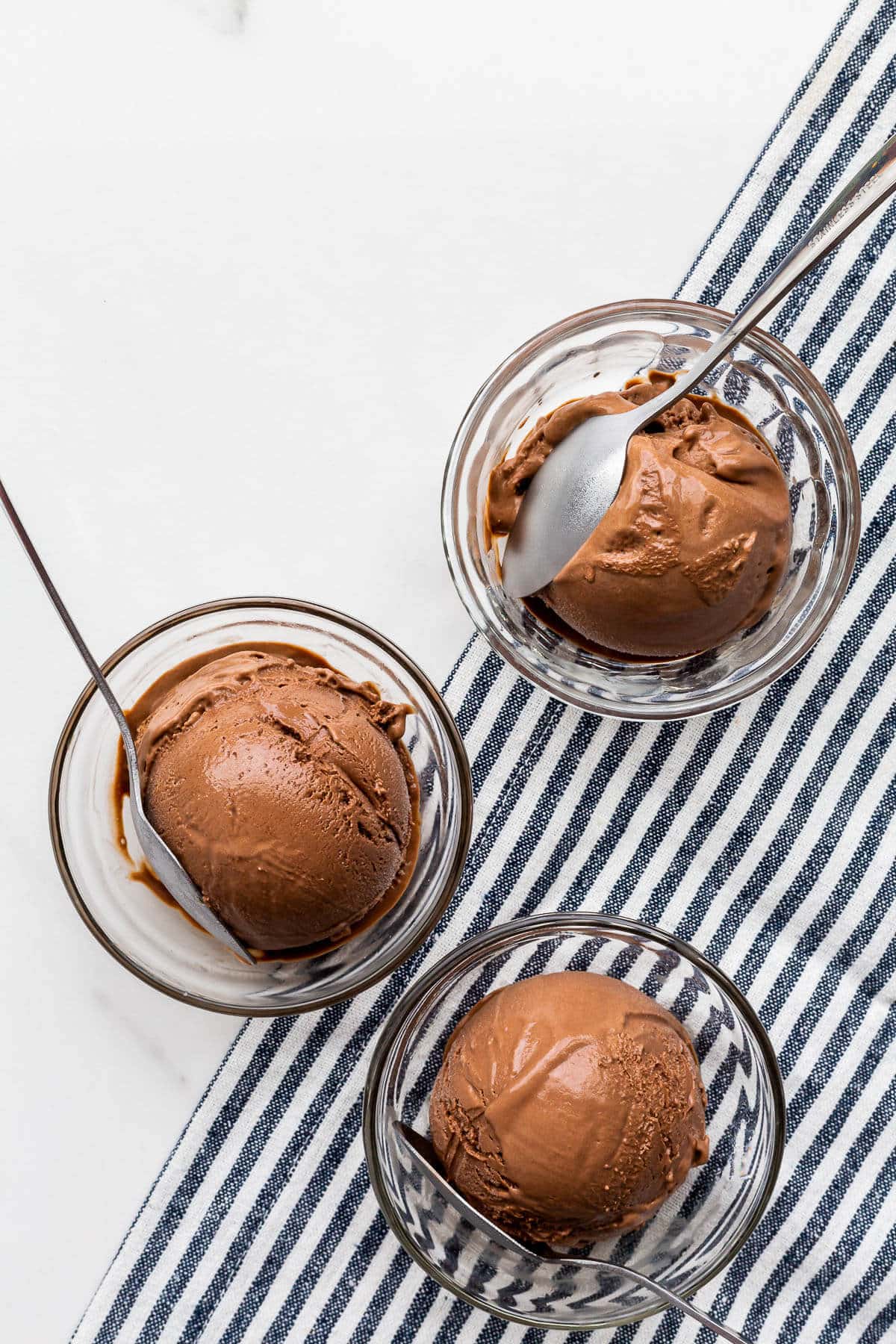 Scoops of homemade chocolate ice cream in glass bowls.