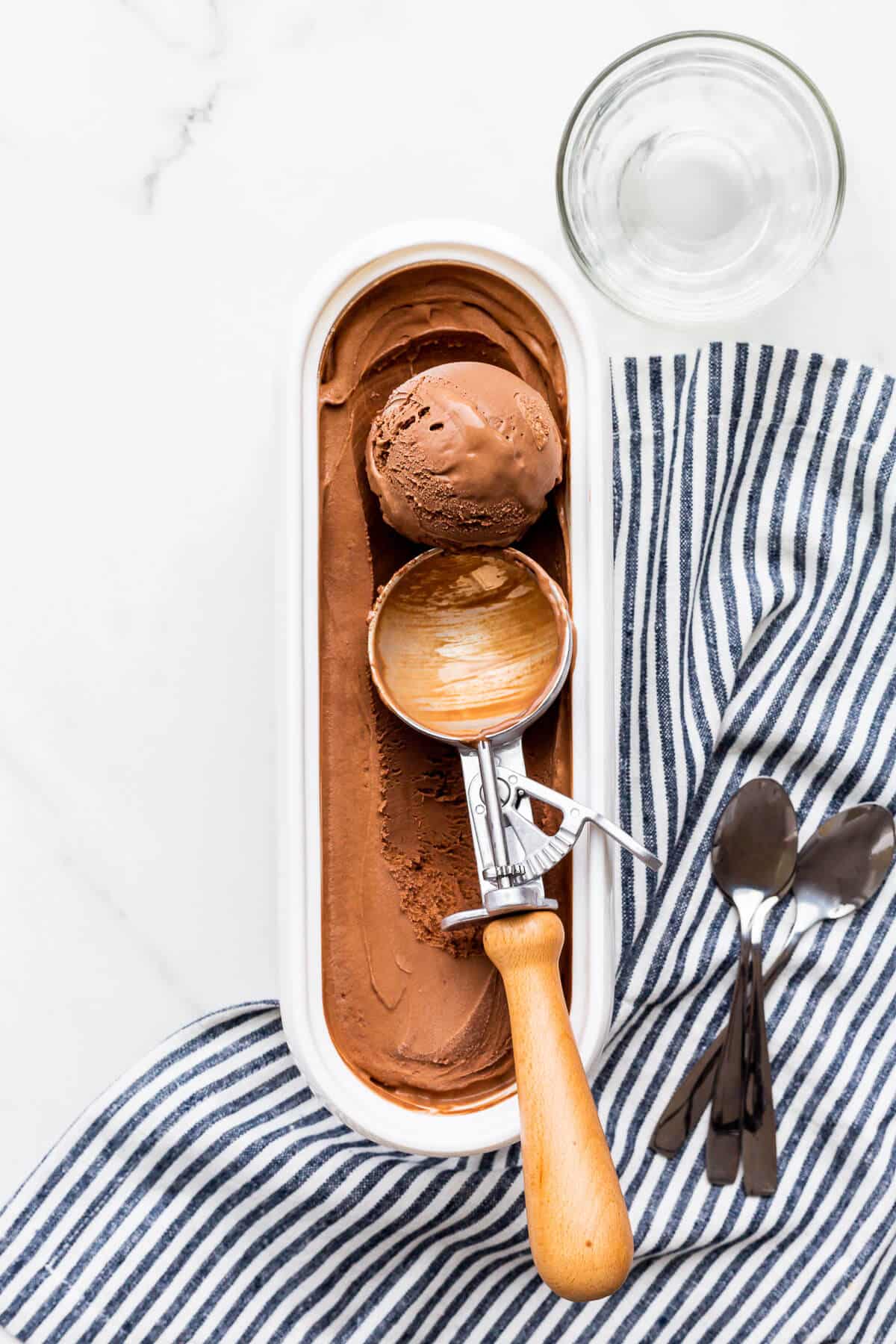 Scooping homemade dark chocolate ice cream with an ice cream scoop.