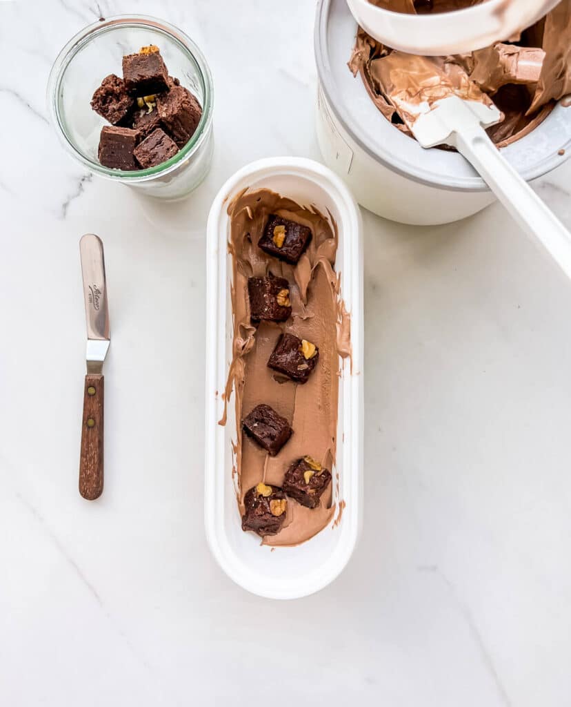 Layering freshly churned chocolate ice cream and brownie pieces to make chocolate brownie ice cream.