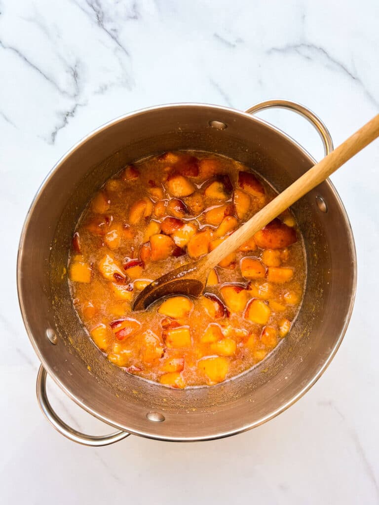 Macerated peaches to make jam in a big pot.