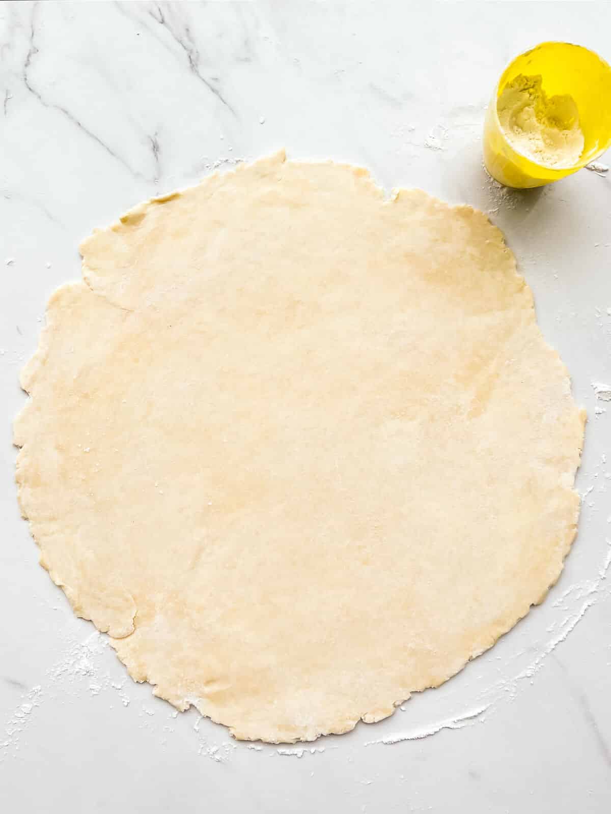 Pie dough rolled out into a round, thin sheet to make a pie crust.