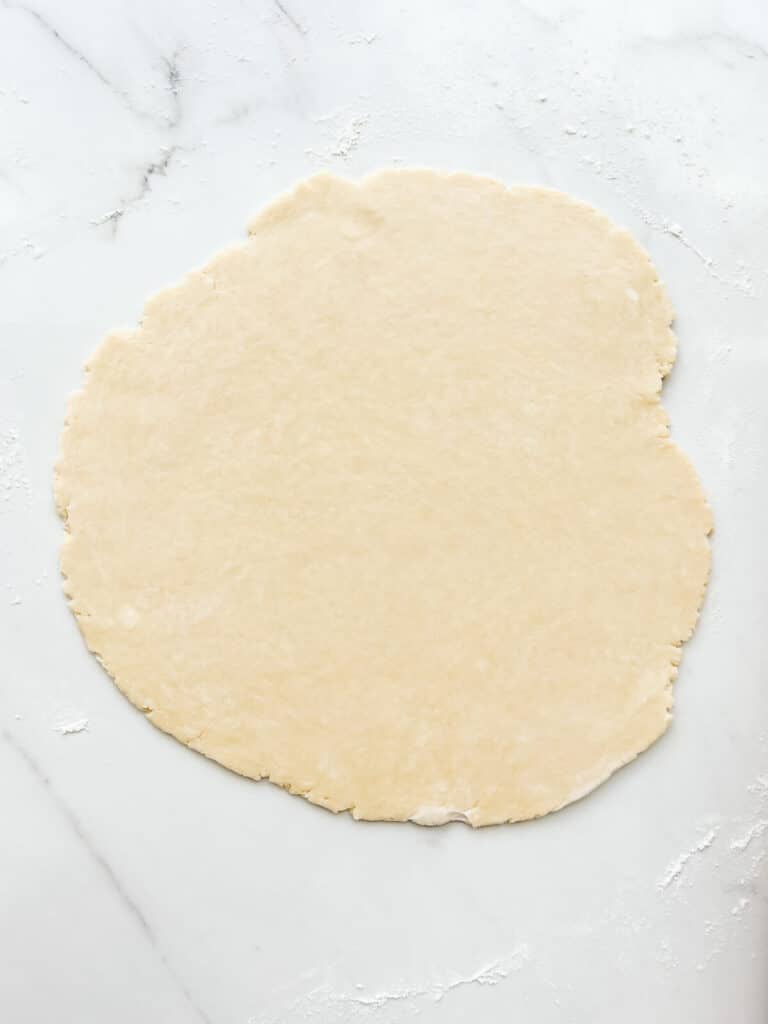 Pie dough rolled out into a round, thin sheet to make a pie crust.