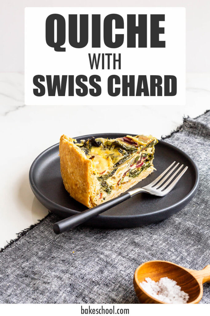 A slice of quiche with rainbow Swiss chard in it on a black plate with a fork, served with a small bowl of salt on the side.