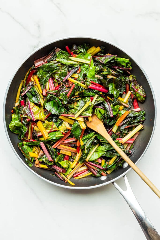 Sautéeing rainbow Swiss chard in a fry pan to make quiche filling.