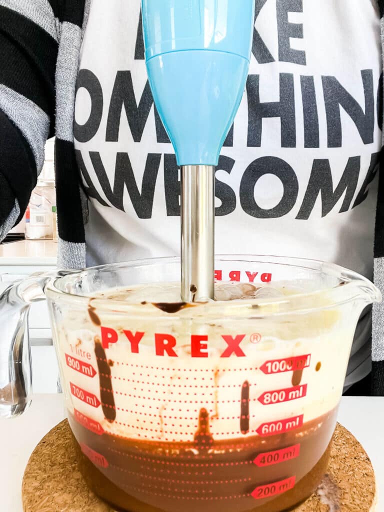 Using an electric stick blender to combine crème anglaise and a mixture of cream, dark chocolate, and cocoa to make a smooth and creamy chocolate ice cream.