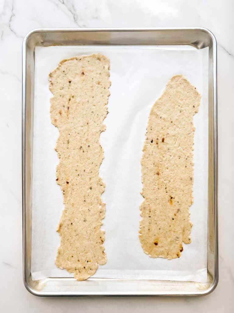Two sheets of cracker dough rolled out thin and placed on a sheet pan lined with parchment.