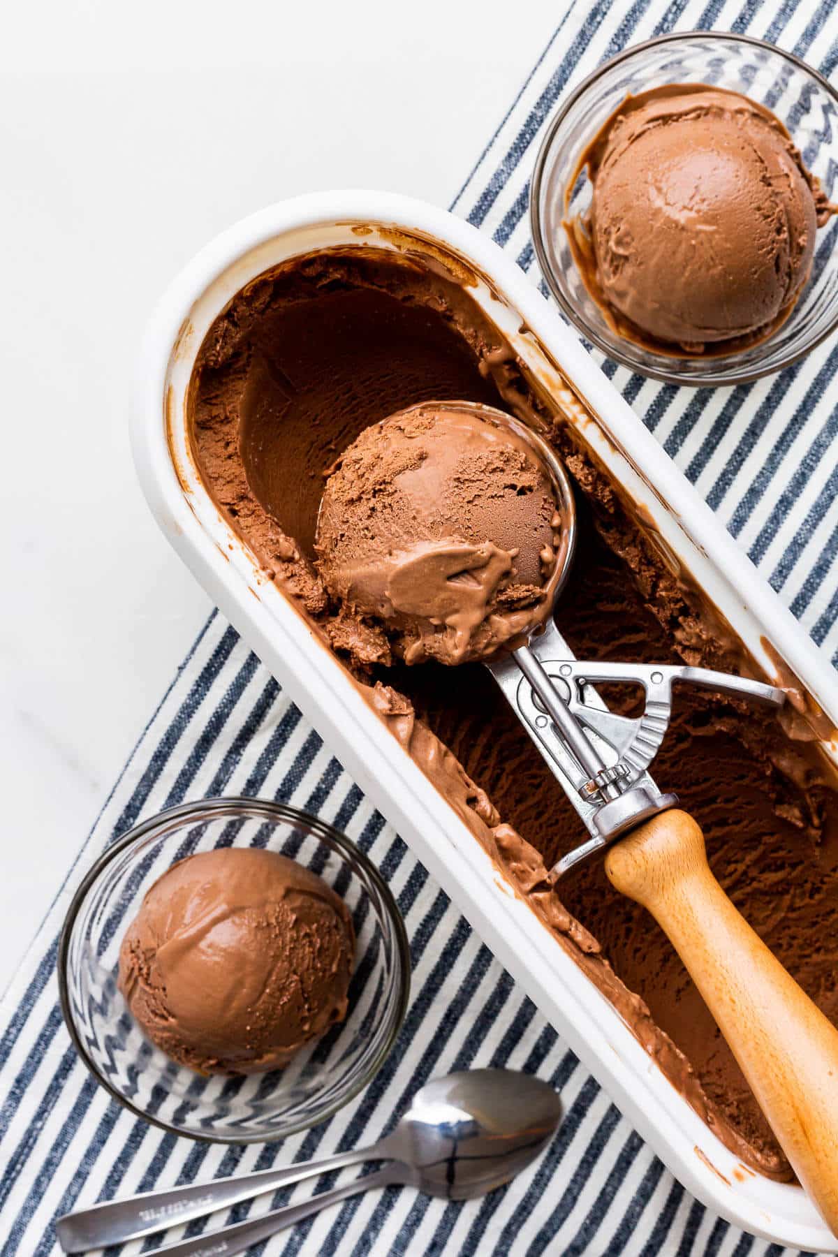 Scooping dark chocolate ice cream into glass bowls to serve.