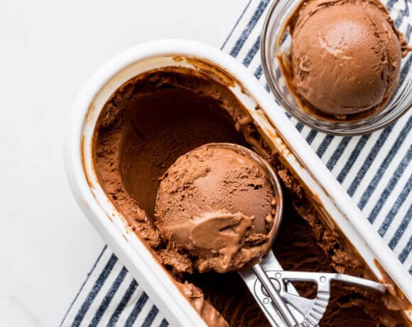 Scooping chocolate ice cream with an ice cream scoop into glass bowls.