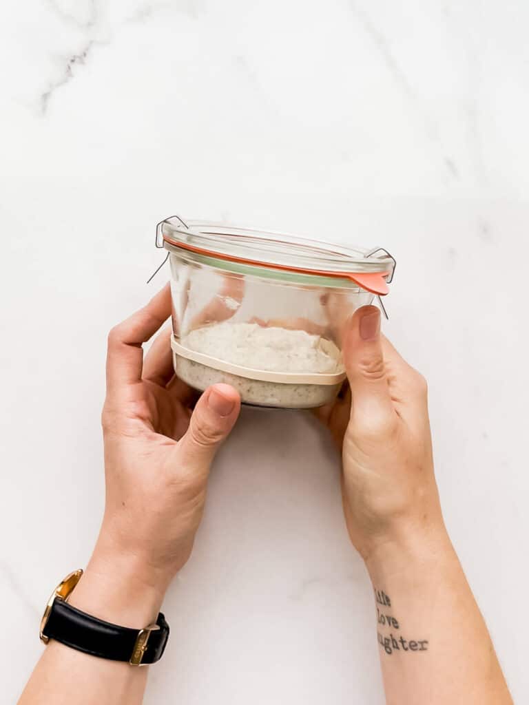 A jar of new sourdough starter with an elastic band to mark the height of the starter before it grows.