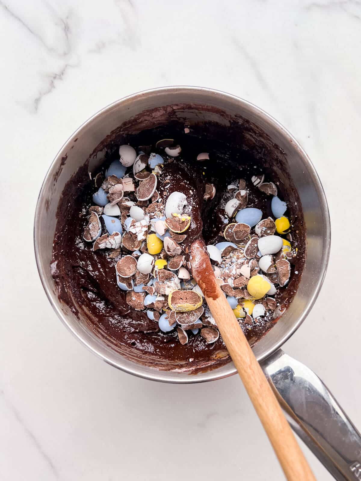 Stirring chopped candy-coated Mini Eggs into brownie batter to make Easter brownies.
