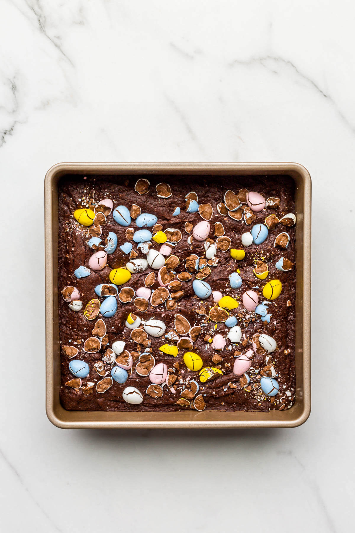 A pan of baked Easter brownies topped with colourful candy Mini Eggs.