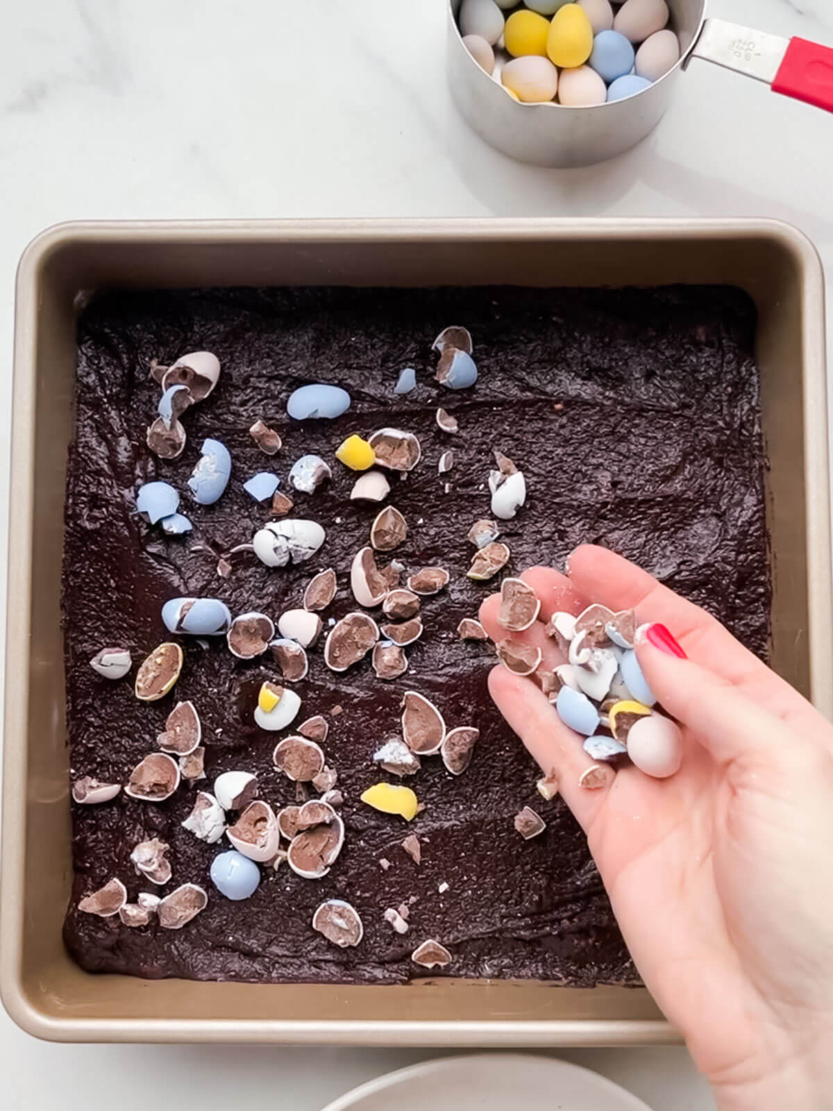 Topping brownie batter with Easter eggs before baking.