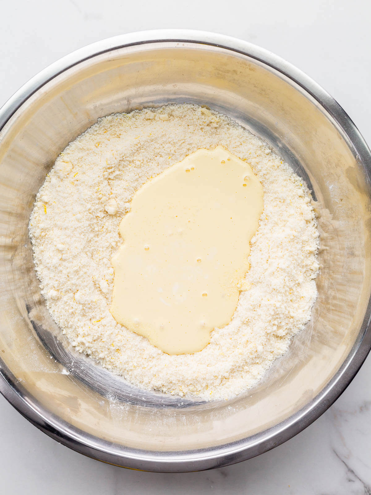 Stirring the mixed wet ingredients into the dry ingredients to make a muffin batter.