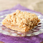 An apple crisp bar made with a crumble topping and an apple sauce filling on a glass plate.