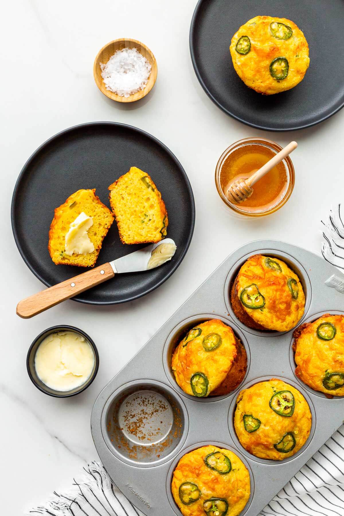 Chilli cheddar cornbread muffins being served with butter and honey on the side.