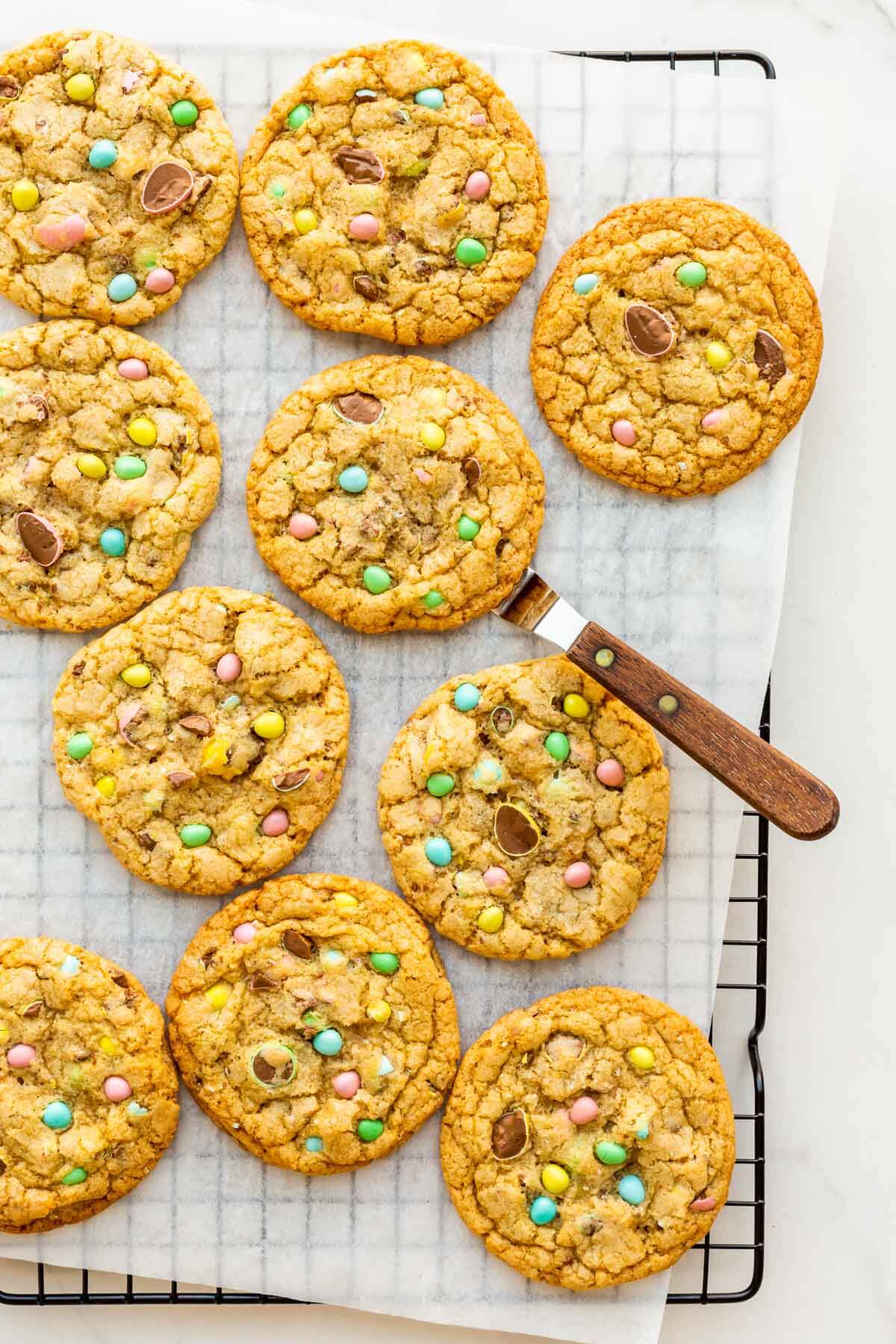 Easter cookies garnished with Mini Eggs cooling on a metal rack.