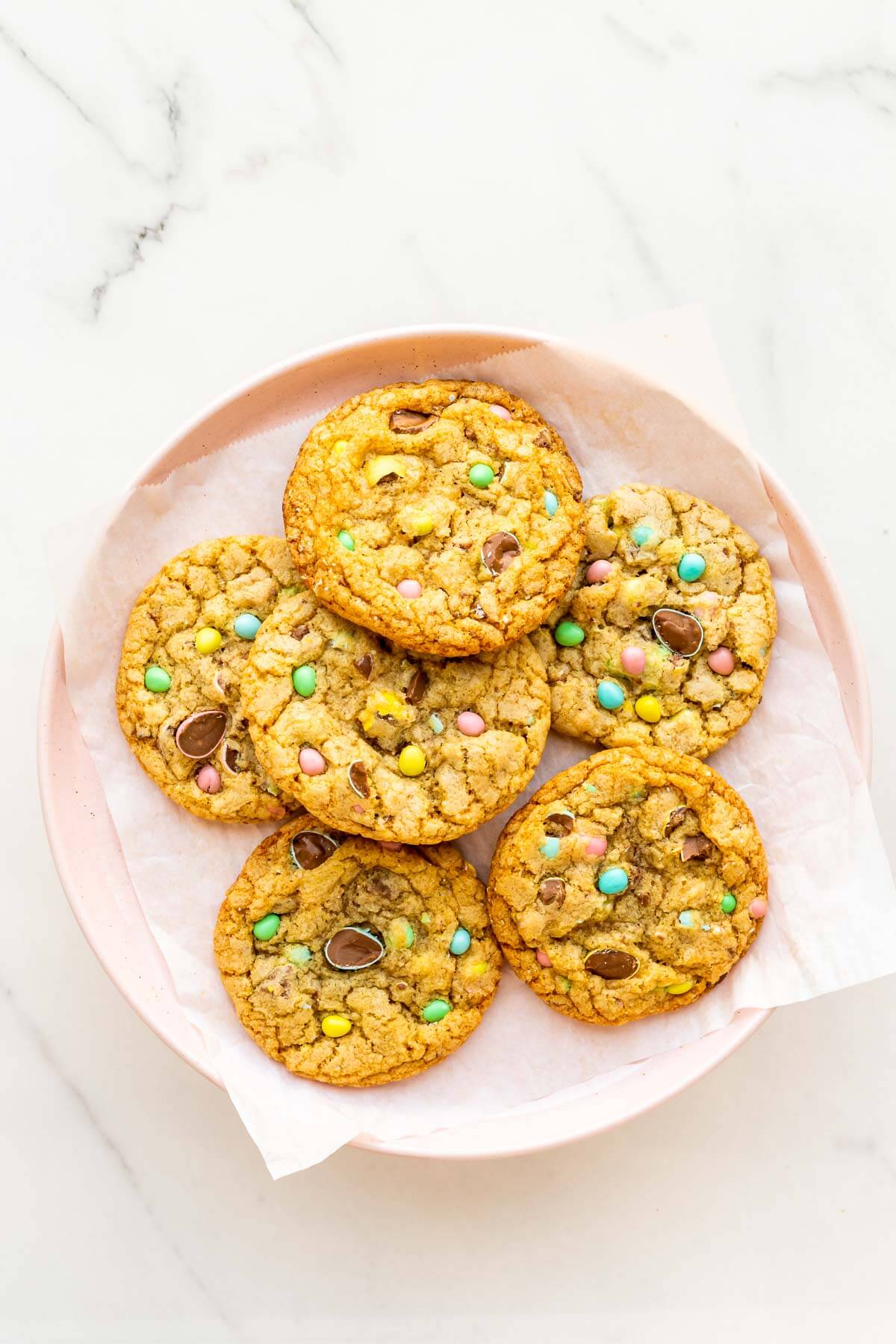 A pink plate of Easter chocolate chip cookies made with Cadbury Mini Eggs.