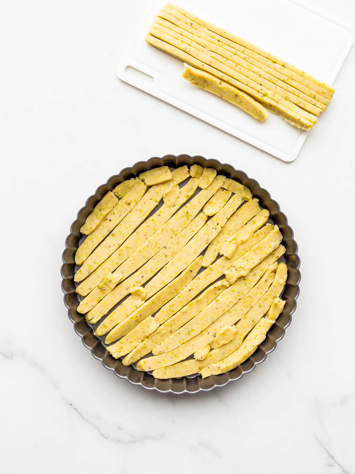 Lining tart pan with thin slices of unbaked sweet dough to make a tart shell.