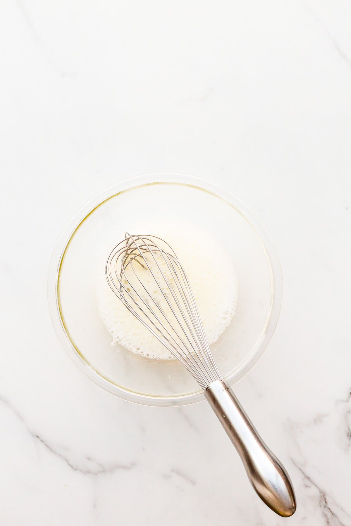 Egg whites whipped in a glass bowl with a whisk until foamy.