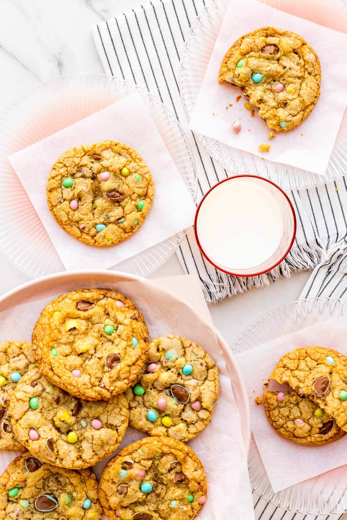 Pink plates of Easter cookies garnished with Mini Eggs served with a glass of milk.