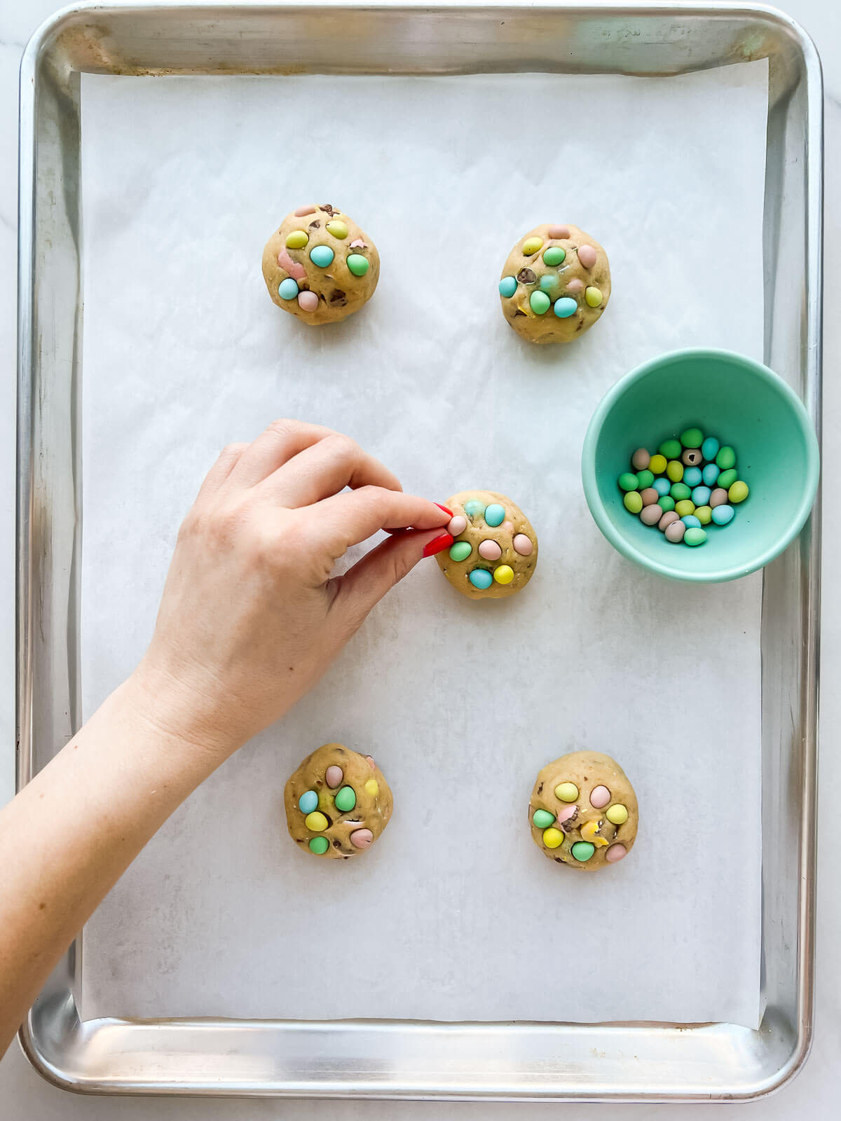 Garnishing chocolate chip cookies with colourful Cadbury Micro Eggs (which are a tiny version of candy-coated Mini Eggs)